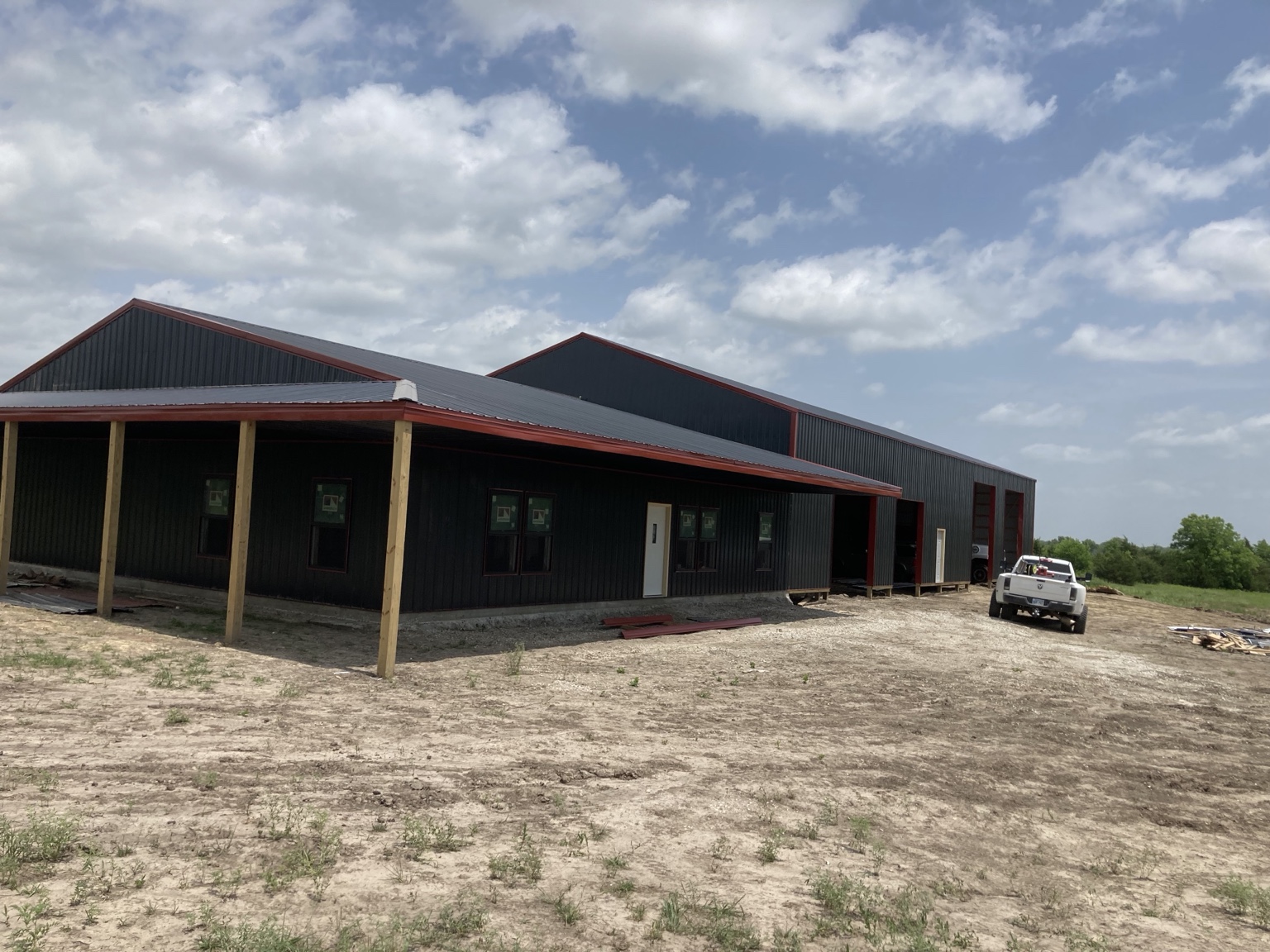 Large black and red pole barn with covered porch